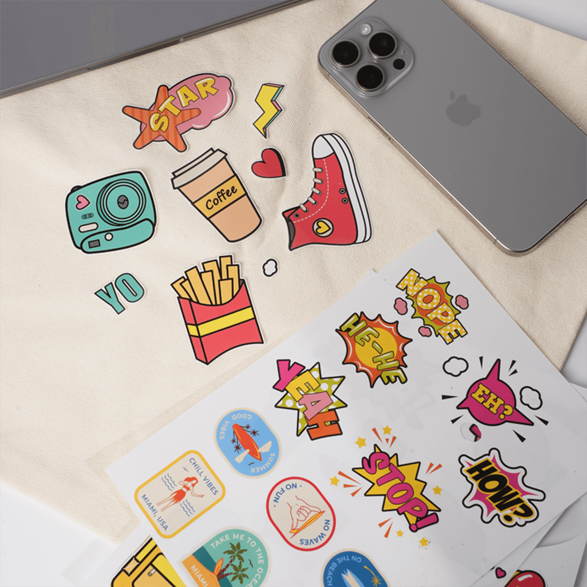 A set of colorful stickers with designs like a camera, coffee, and fries, next to a smartphone.