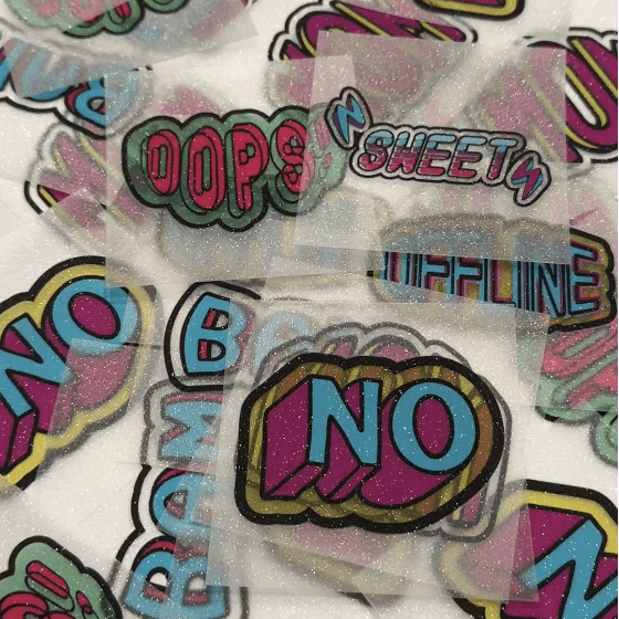  Glittery stickers with colorful text designs scattered on a surface.