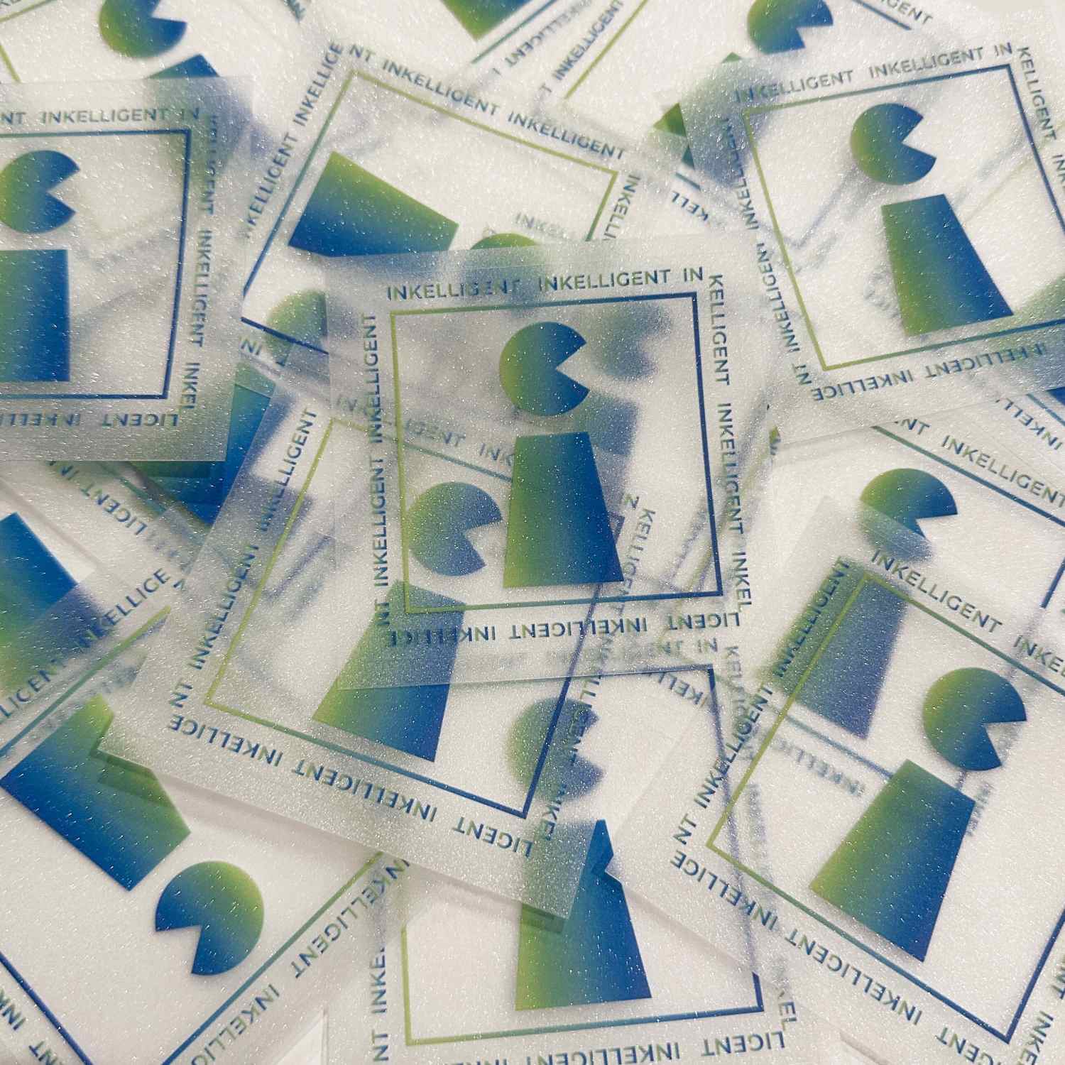 Transparent and glitter stickers with a blue and green gradient design and text 'INKELLIGENT'.