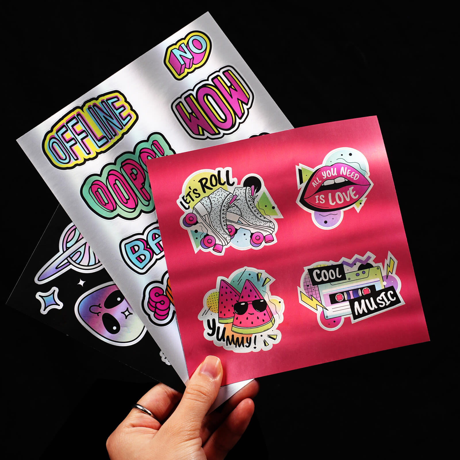 Colorful vinyl sticker sheets with playful designs like roller skates, watermelon, and text phrases on a black background.